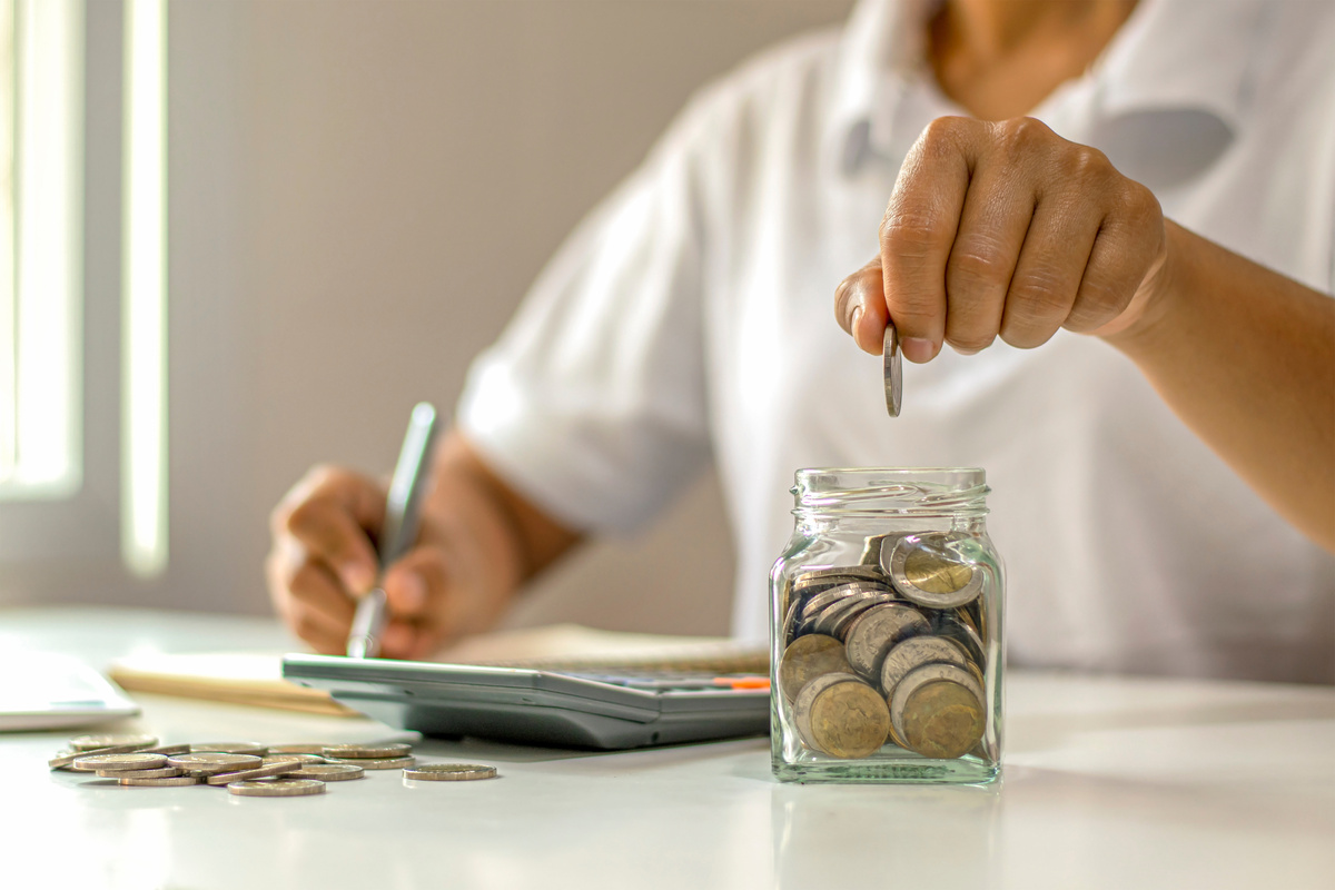 Person Saving Coins in a Jar